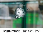 A round trace of bullet coming into the thick window glass after burglary attempt. The bullet-resistant glass (ballistic glass or transparent armor). The attempted armed robbery.