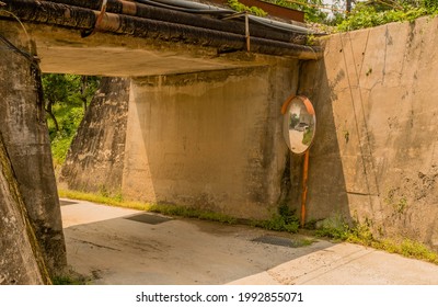 Round Traffic Mirror Beside Rural One Line Concrete Underpass.