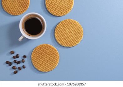 Round Wafers And Cup Of Coffee On Blue Table, Top View