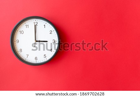 Round wall clock on red surface showing 3 o'clock, layout, top view, place for text