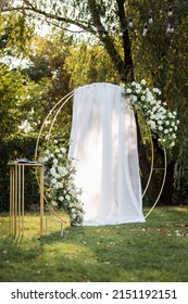 Round Wedding Arch Stands Against The Background Of Trees