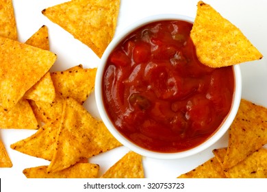 Round White Bowl Of Tomato Salsa Dip With Tortilla Chips Inside And Surrounding, Isolated From Above.