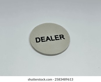 a round white dealer button with the word “DEALER” printed in black, isolated on white