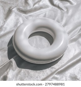 Round, white flotation device sitting on a shimmering, satin-like fabric