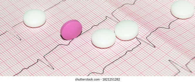 Round White And Pink Tablets On A Paper Cardiogram Close-up, With A Copy Of The Text Space. Cardiac Care. Concept Of Cardiology, Medicine And Insurance.