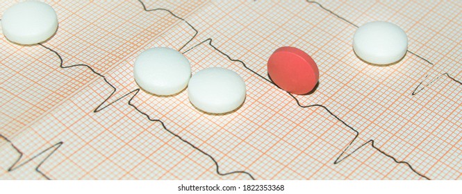 Round White And Pink Tablets On A Paper Cardiogram Close-up, With A Copy Of The Text Space. Cardiac Care. Concept Of Cardiology, Medicine And Insurance.