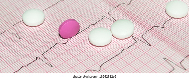 Round White And Pink Tablets On A Paper Cardiogram Close-up, With A Copy Of The Text Space. Cardiac Care. Concept Of Cardiology, Medicine And Insurance.