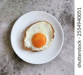 Round white plate with fried eggs isolated on white background. View on table