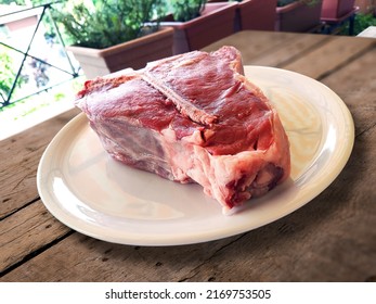 Round White Plate With Raw Fiorentina T-bone Steak Beef Porterhouse On Rustic Wood