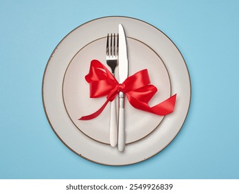 Round white plate and tied with red bow view with knife on yellow background, festive table setting, top view - Powered by Shutterstock