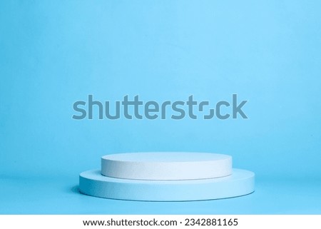 Round white platform podium on pastel blue background. Podium to show cosmetic products.