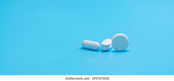 Round White Tablets Pills And Oval Tablets Pills On Blue Background. Pharmacy Shop Banner. Prescription Drugs. Pharmaceutical Industry. Painkiller, Antibiotics, And Antacid Tablet Pills. Pharmaceutic.