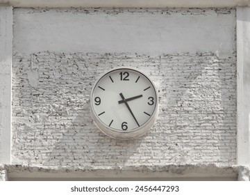 Round white watch face with numbers hanging on white brick wall. Clock dial face in front of brick wall, Space for text, Selective focus. - Powered by Shutterstock