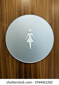 A Round Womens Bathroom Sign On A Wood Door.