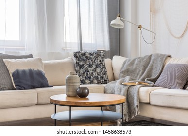 Round wooden coffee table in front of scandinavian corner sofa with pillows - Shutterstock ID 1458638573
