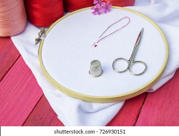 Round Wooden Hoop With White Fabric For Cross Stitch And Coils Of Red Thread