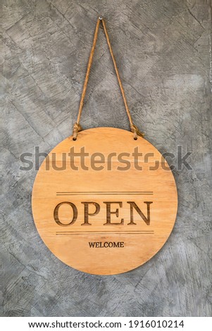 Round wooden open sign on cement background