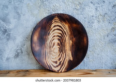 A round wooden plate stands on the table. For decoration, interior and food. On a blue natural background.