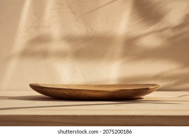 Round wooden podium for food, products or cosmetics against bright brown background with natural sun shadows. Front view.
 - Shutterstock ID 2075200186