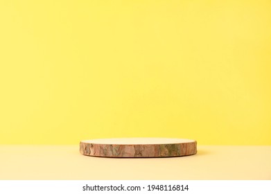 Round wooden podium on beige and yellow background for product presentation. Front view. Copy space.
