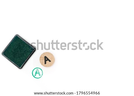 round wooden stamp letter A stamped and pad with green ink