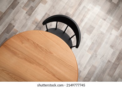 Round wooden table and black chair indoors, top view