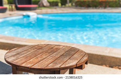 Round wooden table and blurred empty swimming pool on day light - Shutterstock ID 2138016325