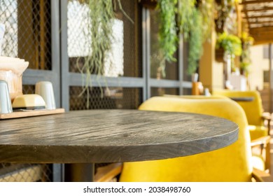 Round wooden table and cozy yellow chair at street cafe. Vacant restaurant furniture on the terrace outdoors. - Powered by Shutterstock