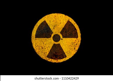 Round yellow and black radioactive (ionizing radiation) nuclear danger symbol on rusty metal grungy texture and isolated on dark black background.