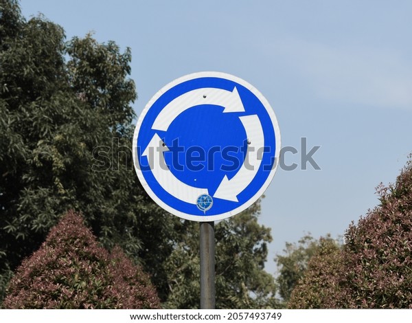 roundabout traffic sign, circular directions,\
white arrow on blue\
base\

