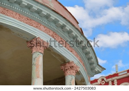 Rounded corner of Eclectic-style stately home with porch of Corinthian columns supporting a Baroque entablature in light-salmon and mint-green chipping paint, Presidentes avenue-El Vedado. Havana-Cuba