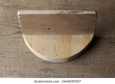 ROUNDED PIECE OF WOOD ATTACHED TO A RECTANGULAR SHAPED PIECE OF WOOD AT AN ANGLE