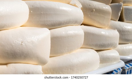 Rounds of fresh cheese stacked on the table, ready for sale. 