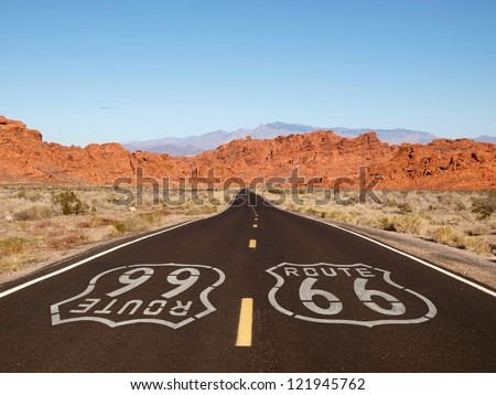 Route 66 pavement sign with Mojave desert red rock mountains.