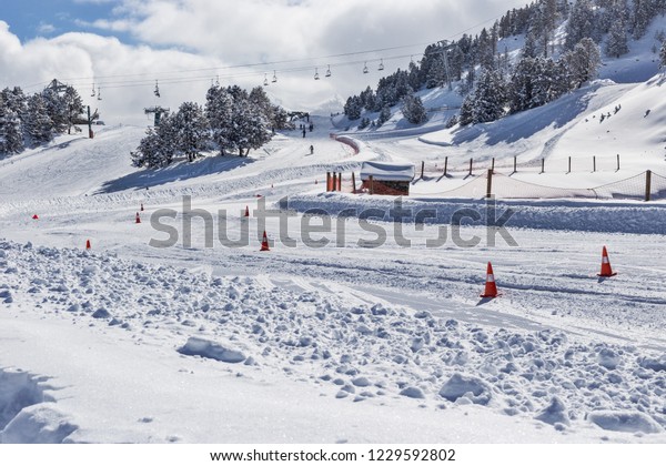 The route for test-drive cars in difficult\
conditions in the mountains - the Pyrenees, Andorra. The road is\
covered with snow, with descents and ascents, the road is marked by\
road cones.