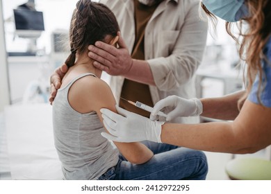 Routine vaccinations for a child. Father holding small girl while pediatrician injecting vaccine in her arm. - Powered by Shutterstock