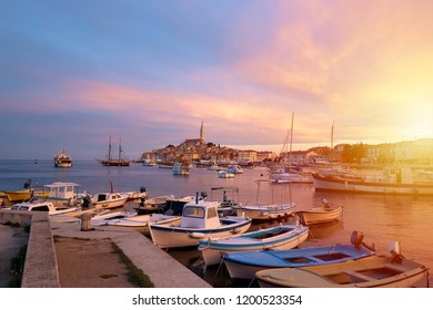 Rovinj, old costal town of Croatia in golden sunrise light. Motorboats, boats and yachts on water in port of Rovinj. High tower of Church of Saint Euphemia. Istra region, popular touristic destination
