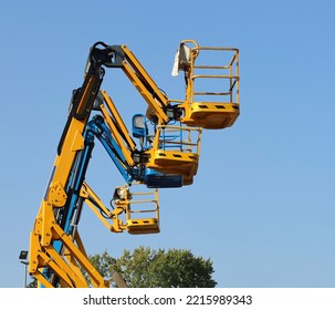 Row Of Aerial Working Platforms Of Cherry Picker,  Side By Side Against Blue Sky.