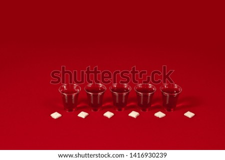 row of alternating communion cups and bread against red background-copy space above-horizontal position