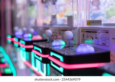 A row of arcade game controllers with neon lights. The controllers are brightly lit and colorful, creating a fun and exciting atmosphere - Powered by Shutterstock