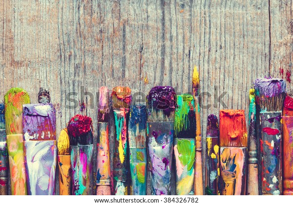 Row of artist paint brushes closeup on old wooden background.