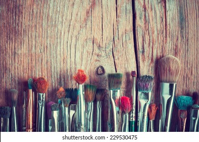 row of artist paintbrushes closeup on old wooden rustic table, retro stylized