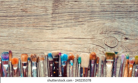 Row of artist paintbrushes closeup on old wooden rustic background - Powered by Shutterstock