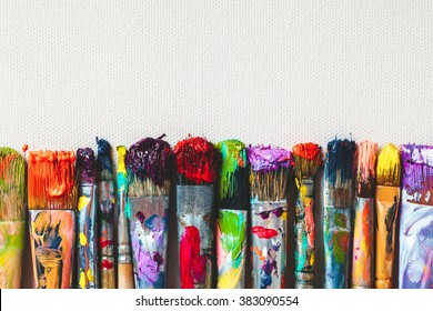 Row of artist paintbrushes closeup on artistic canvas.