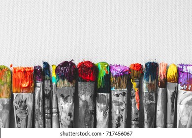 Row of artist paintbrushes with colorful bristle closeup on artistic canvas background, retro black and white stylized. - Shutterstock ID 717456067
