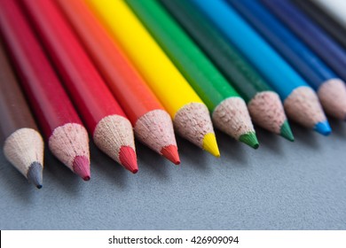 A row of assorted colored pencils on a grey background.