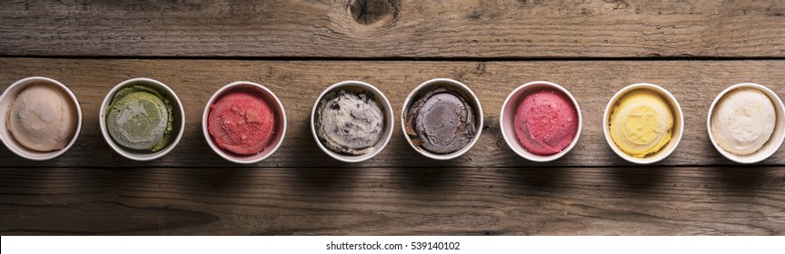 Row of assorted flavors and colors of gourmet Italian ice cream on wood table