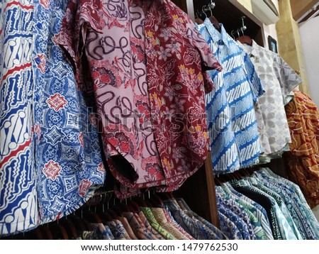a row of batik shirts in a batik shop. batik is the art of coloring cloth from Indonesia.