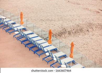 Row Of Beach Lounge Chairs With Orange Umbrellas On Santa Cruz Beach, Santa Cruz, California, USA