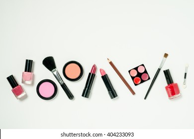 A Row Of Beauty Cometics That Includes Nail Lacquer, Lipstick, Lip Color, Cheek Blush, And Brushes.